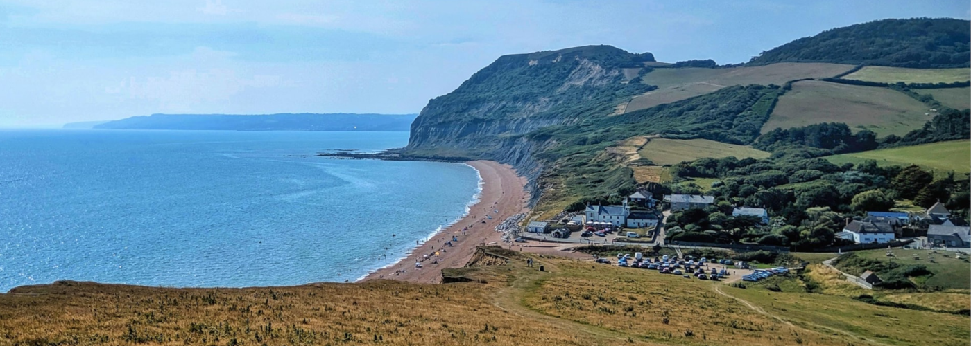 Scenic photo of the Jurassic Coast, featuring a blue sea, cliffs and sand dunes